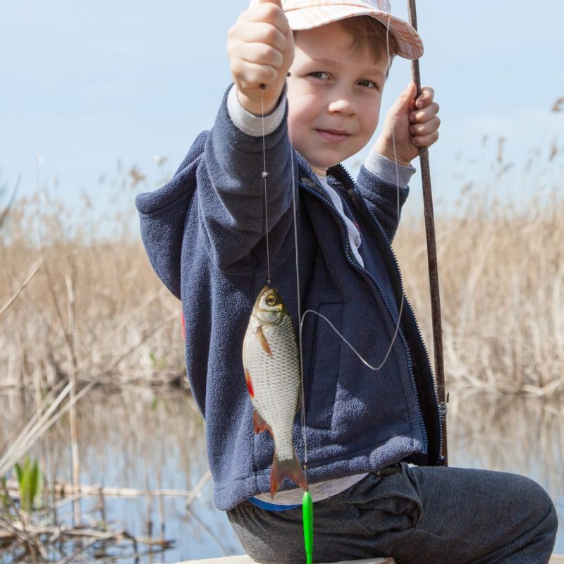 Happy boy holding a fish caught in the pond